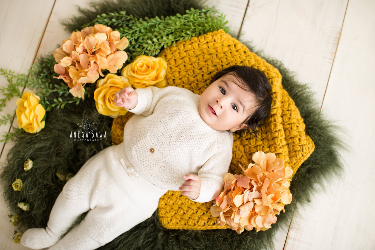 Captivating baby boy photoshoot showcasing the delightful 6, 5, 4, 3-month-old on a vibrant yellow and green rug against a pristine white backdrop. Skillfully captured by Anega Bawa, the esteemed baby photographer in Delhi, Gurgaon, and Noida.