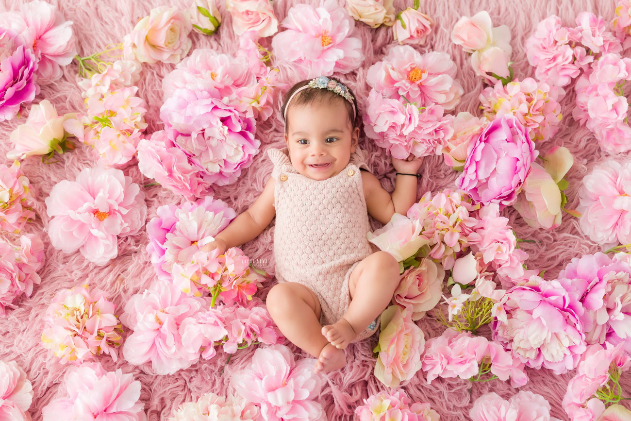 Baby girl photo shoot, 6 or 5 or 3 or 4 months, baby pink baby suit, pink rug, flowers on floor. Location: Delhi, Gurgaon, Noida. Photographer: Anega Bawa.