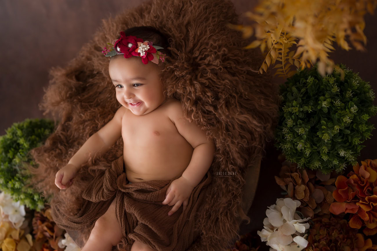 Baby girl photo shoot, 6 or 5 or 3 or 4 months, brown rug, brown wrap, green yellow shrubs. Location: Delhi, Gurgaon, Noida. Photographer: Anega Bawa.