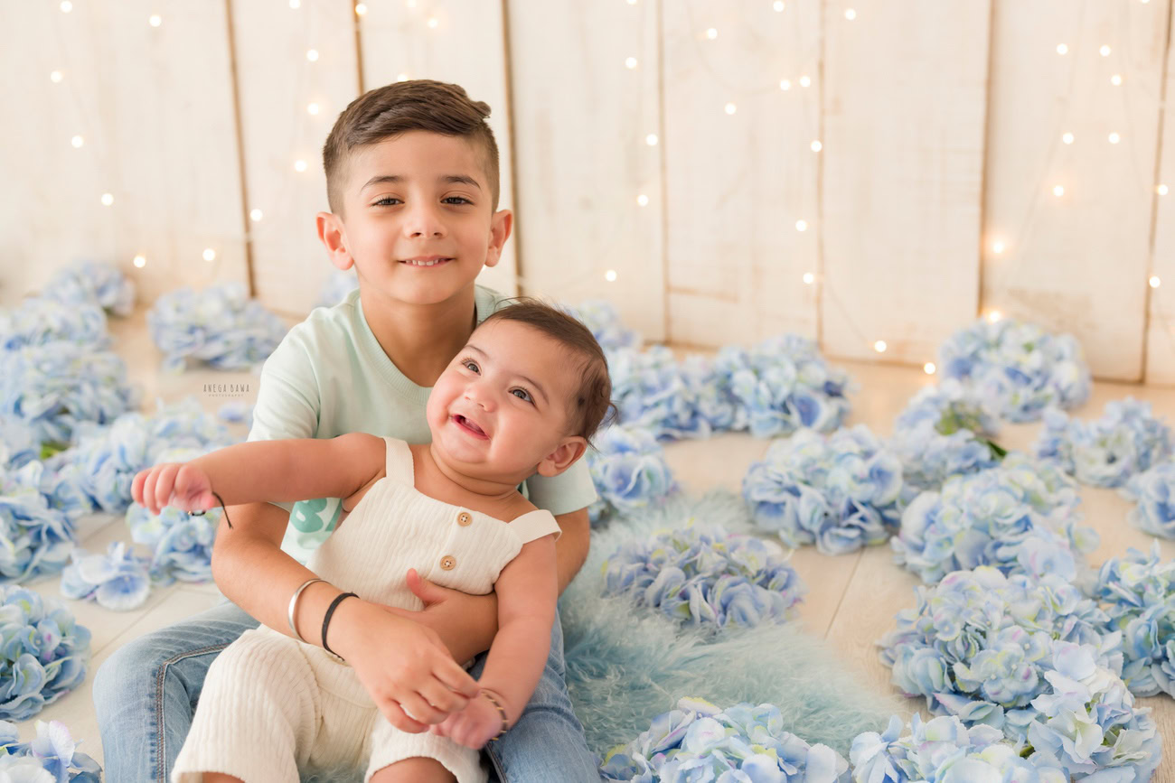 Baby girl photographer, 3, 4, 5, or 6 months, peach baby suit, pink flower backdrop, cute headband. Location: Delhi, Gurgaon, Noida. Photographer: Anega Bawa.