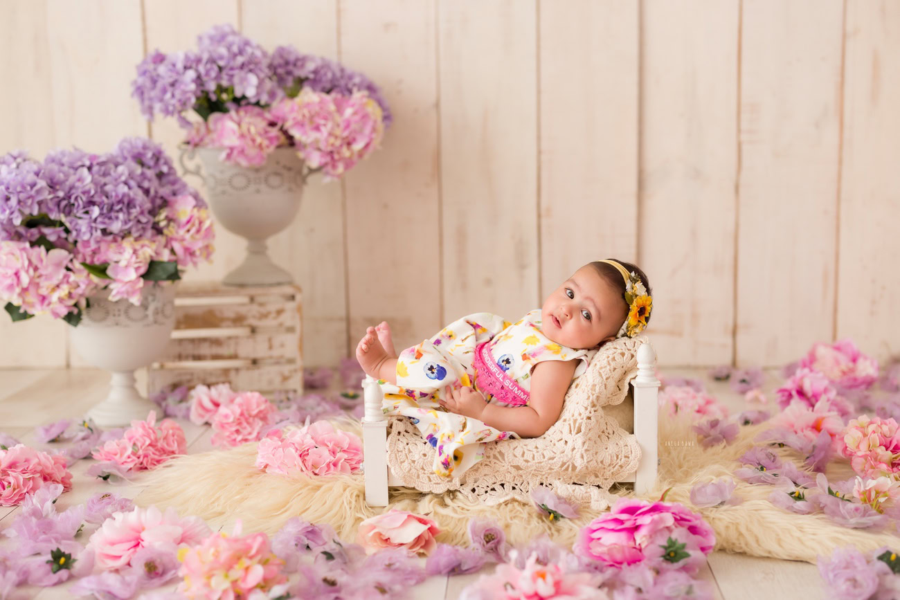 Capture the charm of your little princess at 3, 4, or 5 months against a beige backdrop, adorned with a delicate beige rug and a vase of pink and lavender flowers. Complete the look with a cute headband. Book your baby girl photography session in Delhi, Gurgaon, or Noida with Anega Bawa now!