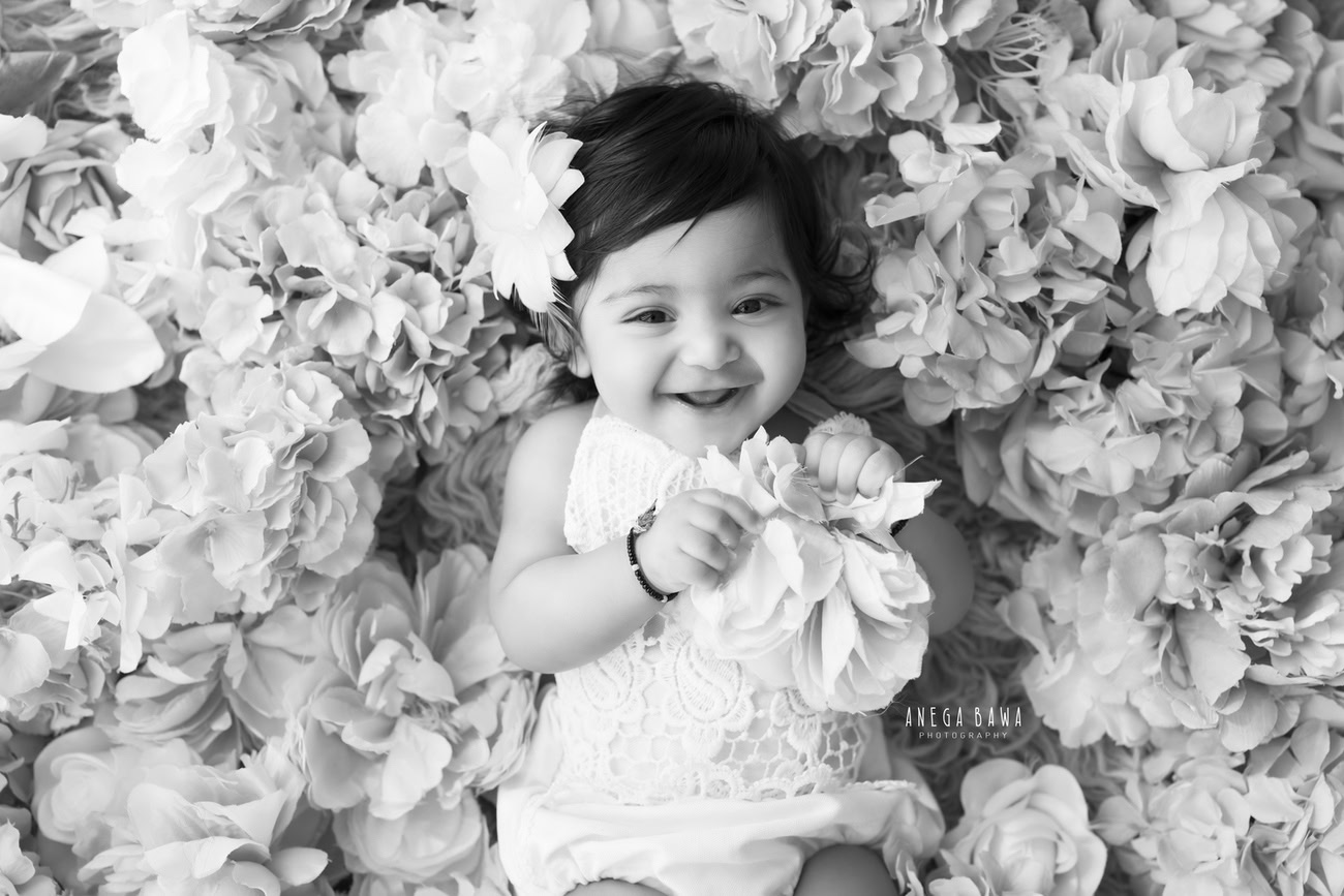 Capture the innocence of your little princess amidst a timeless black and white floral backdrop. Trust Anega Bawa's expertise for captivating baby girl photography sessions in Delhi, Gurgaon, or Noida.