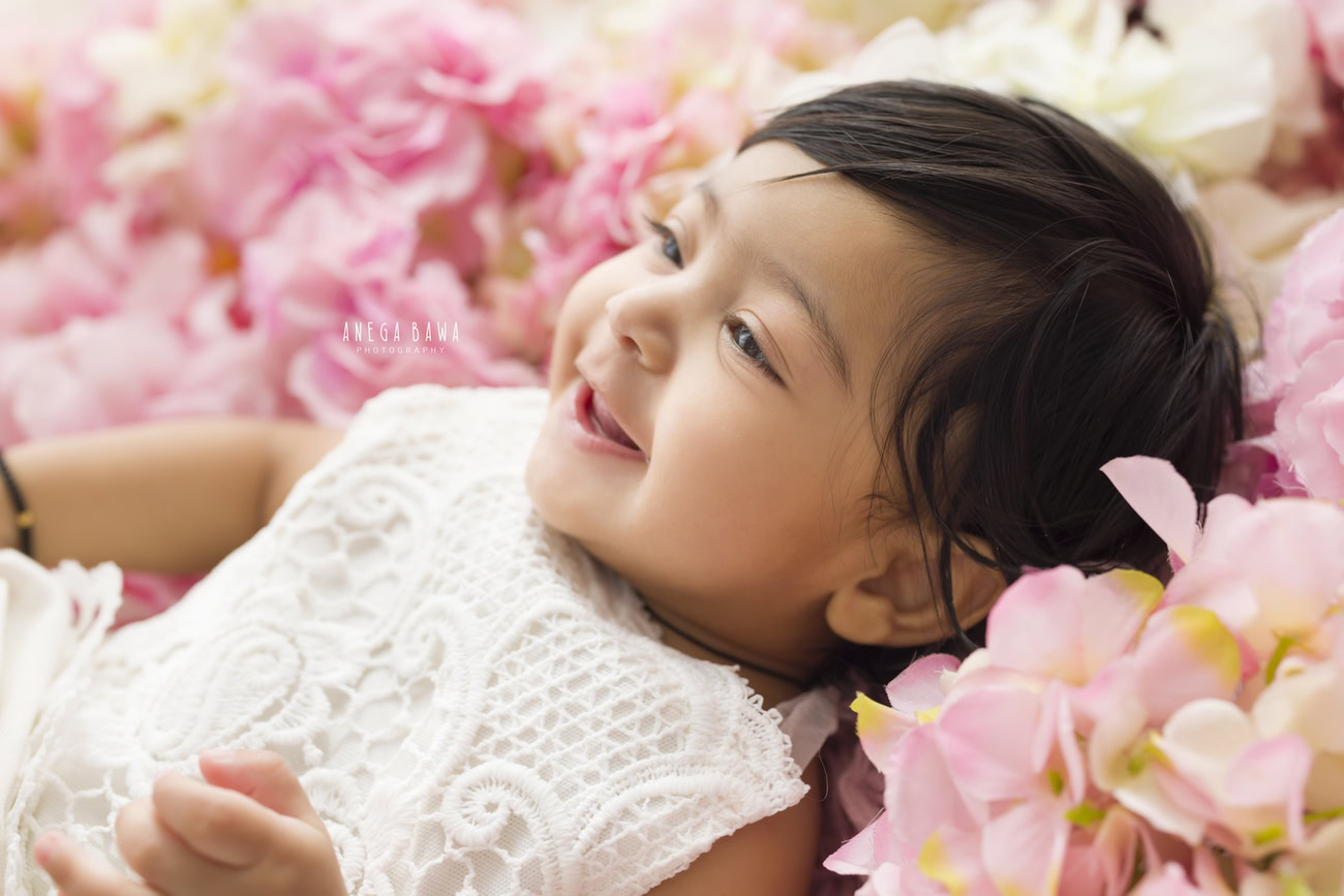 Capture the joyous smiles of your baby girl against a beautiful floral backdrop with Anega Bawa's photography sessions in Delhi, Gurgaon, or Noida.