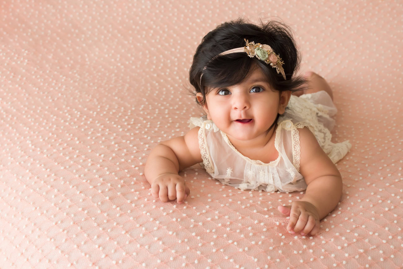 Capture the precious moments of your 3 to 5-month-old baby girl with a peach backdrop and a cute headband. Contact Anega Bawa for exquisite baby girl photography in Delhi, Gurgaon, or Noida.