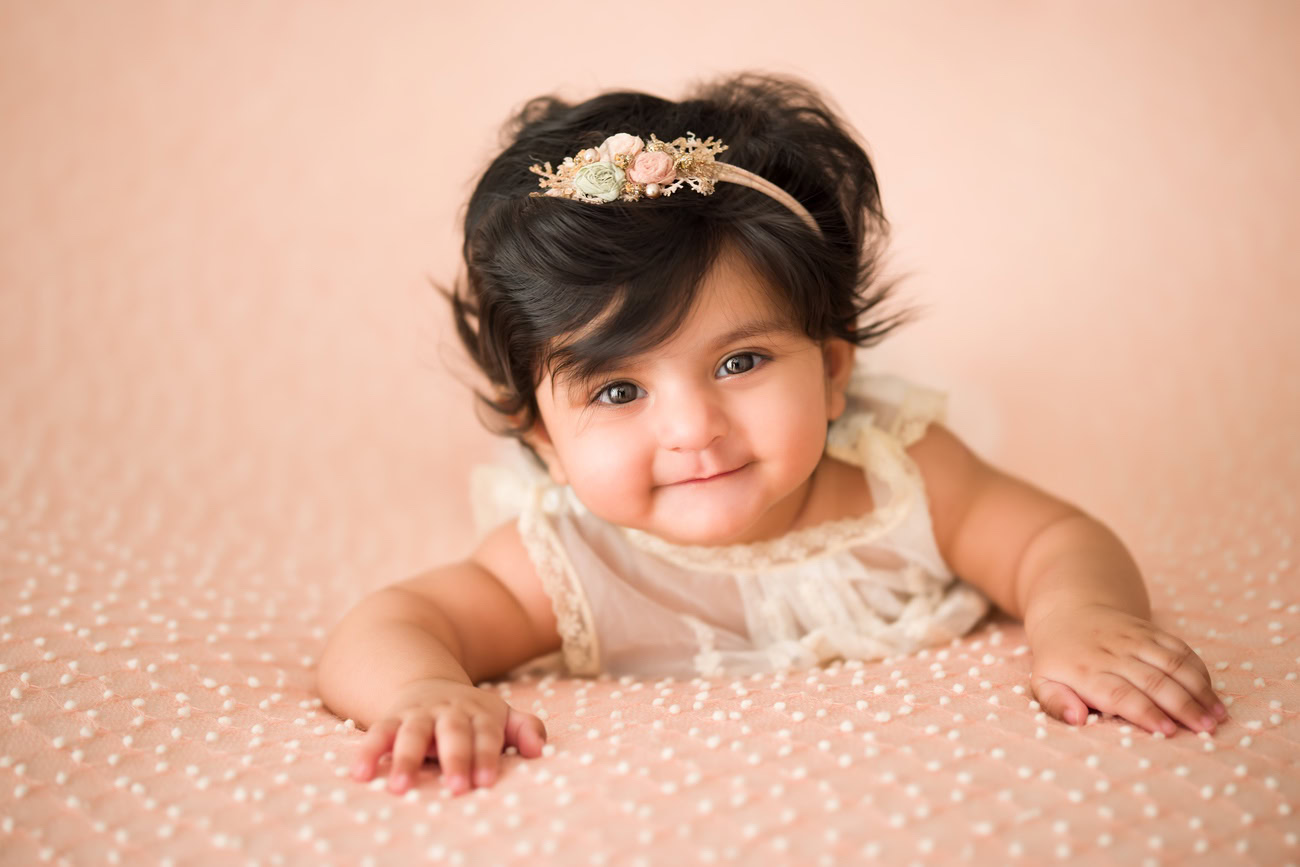 Create timeless memories of your 3 to 5-month-old baby girl with a peach backdrop and a cute headband. Contact Anega Bawa for professional baby girl photography in Delhi, Gurgaon, or Noida.