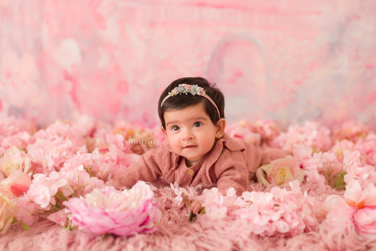 Baby girl photography, 6, 4, 3, or 5 months, pink backdrop, pink flowers on floor, pink rug. Location: Delhi, Gurgaon, Noida. Photographer: Anega Bawa.