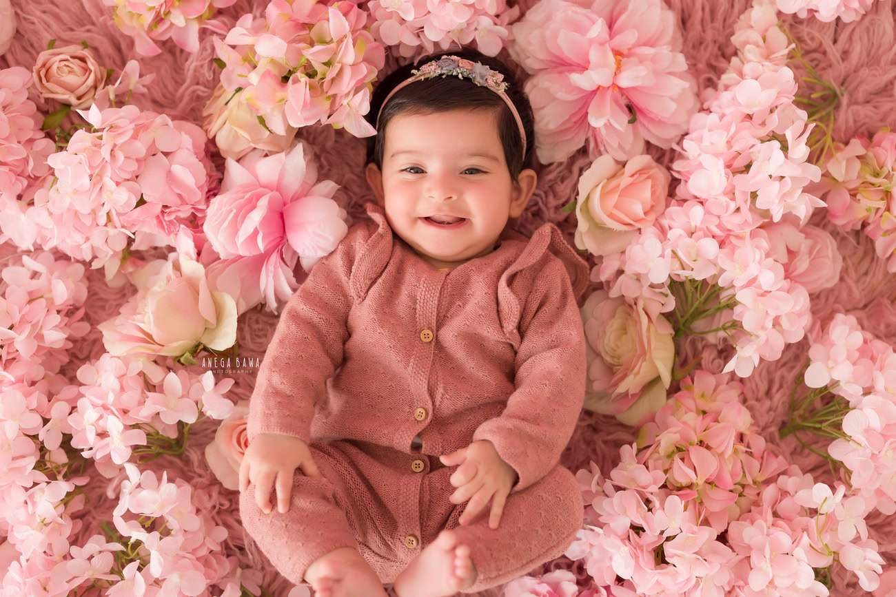 Baby girl photoshoot, 3, 4, 5, or 6 months, baby suit, pink rug, pink flowers, cute headband. Location: Delhi, Gurgaon, Noida. Photographer: Anega Bawa.