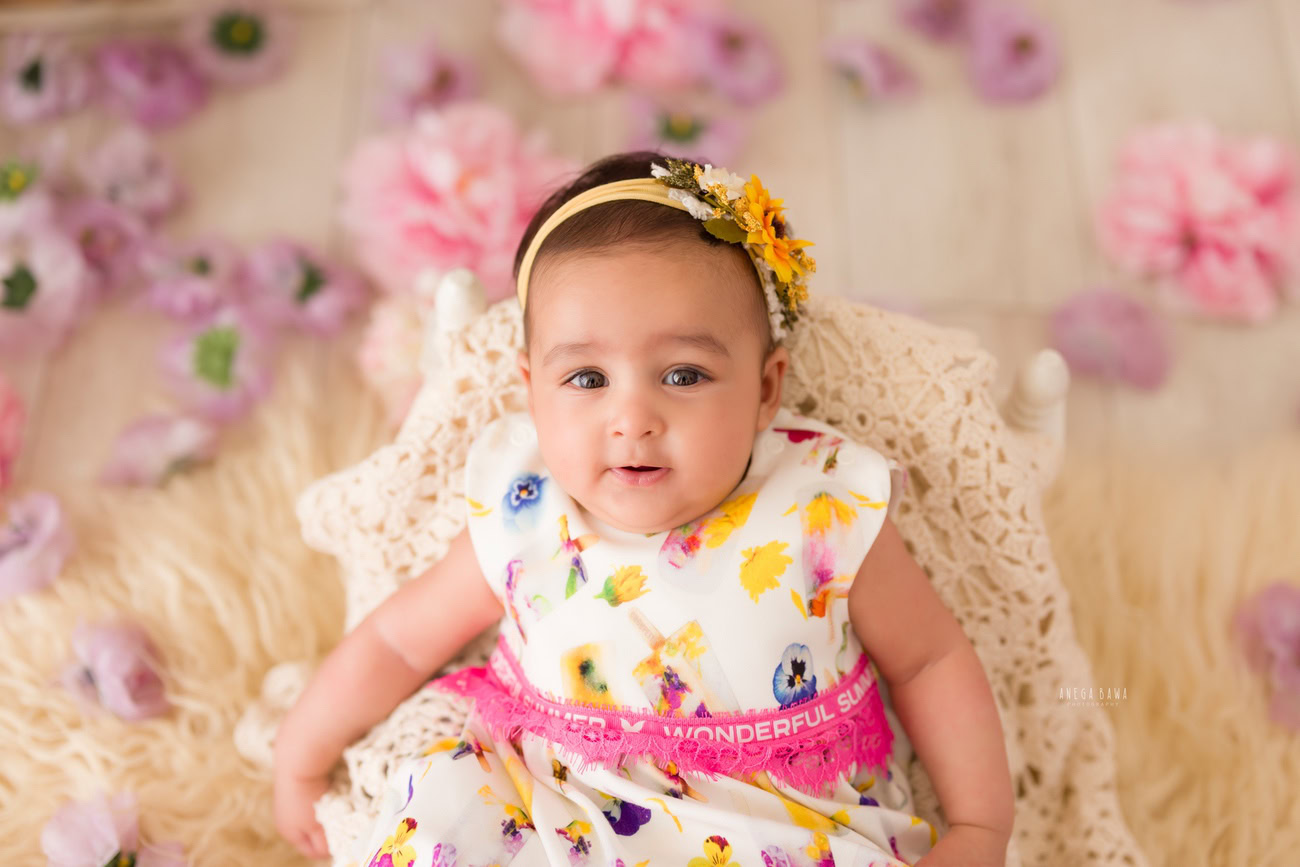 For a charming baby girl photoshoot at 3, 4, 5, or 6 months, envision a scene with a beige rug and a cute headband. Book your session with Anega Bawa in Delhi, Gurgaon, or Noida.
