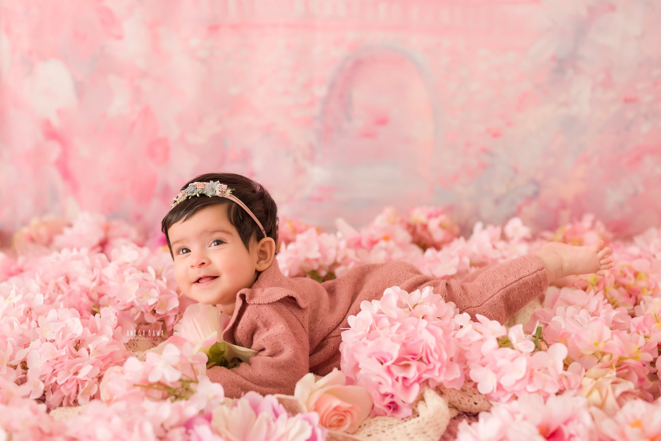 Baby girl photoshoot, 3, 4, 5, or 6 months, peach baby suit, pink flowers, pink backdrop. Location: Delhi, Gurgaon, Noida. Photographer: Anega Bawa.