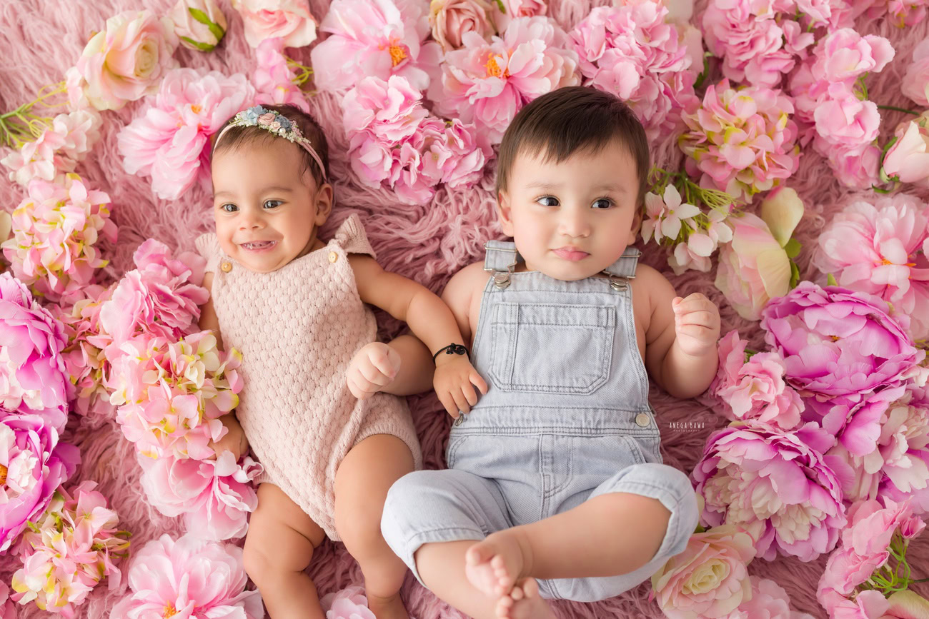 Baby girl photoshoot, 3, 4, 5, or 6 months, pink baby suit, sibling, floral pink backdrop. Location: Delhi, Gurgaon, Noida. Photographer: Anega Bawa.