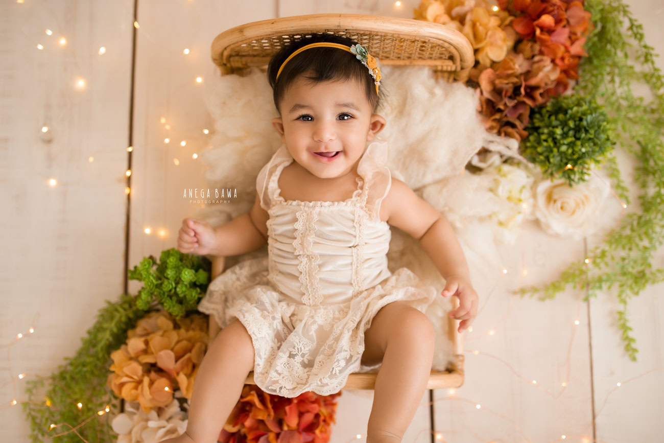 Immerse in the enchanting aura of your baby girl's journey with a delightful photoshoot! Featuring a wooden cot adorned with orange and brown flowers illuminated by golden lights, this session promises to encapsulate precious moments. Contact Anega Bawa to schedule your session in Delhi, Gurgaon, or Noida.