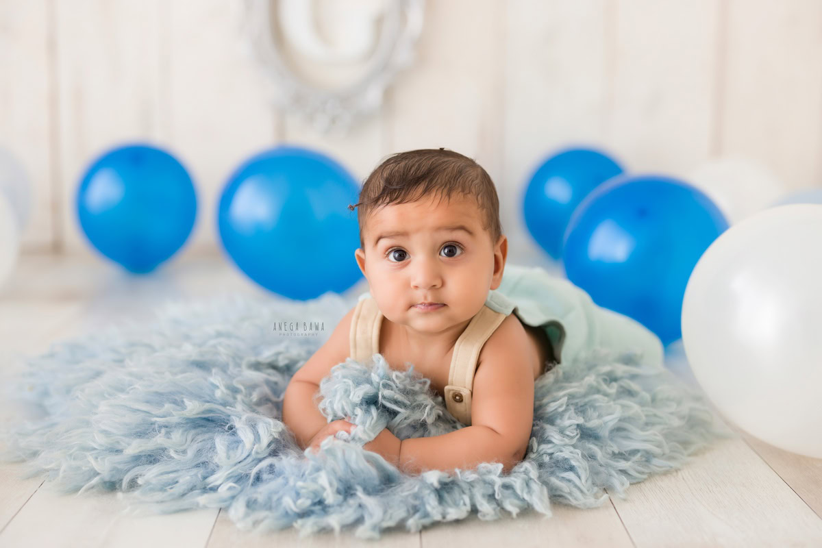 Capture the joy of your little crawler with Anega Bawa Photography's sitter photography in Delhi and Gurgaon. Imagine him exploring amidst a sea of blue and white balloons, set against a crisp white backdrop. These charming moments, at eight months old, are perfect for creating timeless memories.