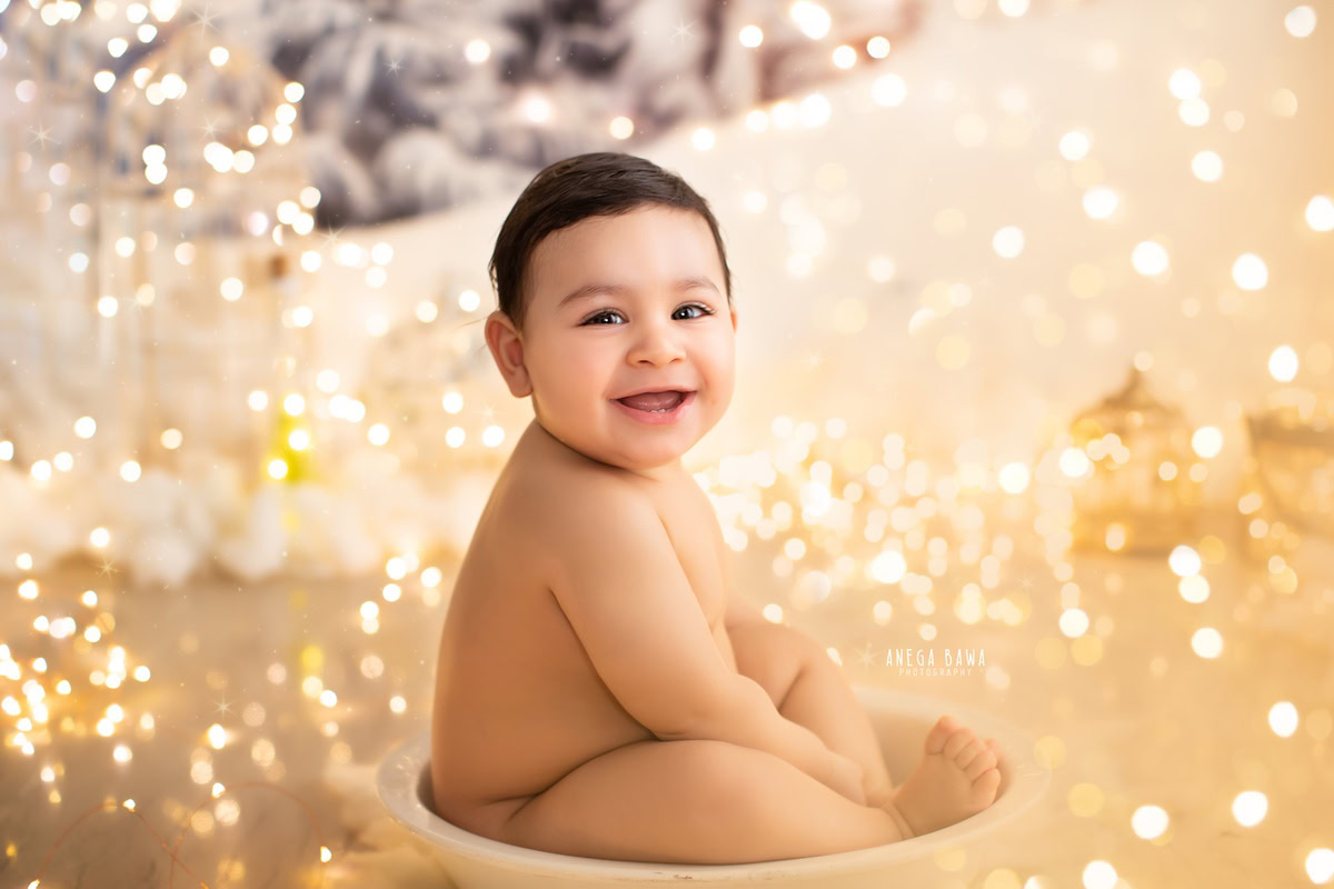 Captured by sitter photographer Anega Bawa in Delhi, a delightful 9-month-old boy is nestled in a beige tub, surrounded by ethereal fairy lights against a soothing beige backdrop.