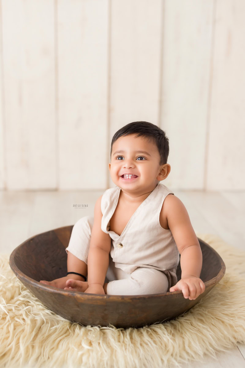 Capture the innocence and joy of your little one with Anega Bawa Photography's sitter photography in Delhi and Gurgaon. Picture your 10-month-old boy seated in a brown tub, surrounded by a cozy beige rug, against a serene beige backdrop. These timeless moments will be treasured for years to come.