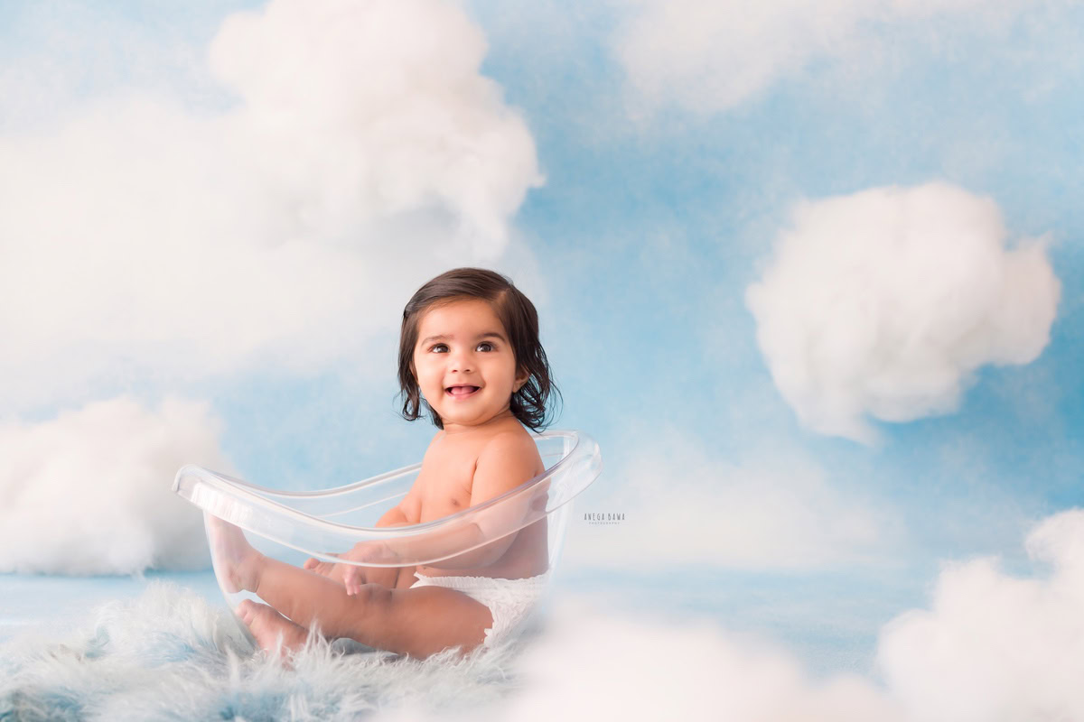 For the sitter birthday photoshoot in Delhi by Anega Bawa, this 10-month-old boy takes center stage in a crystal tub, adding a touch of elegance and luxury to the scene. The cloudy backdrop creates a dreamy atmosphere, enhancing the overall aesthetic of the photoshoot. With his innocent charm and curious expression, the little one becomes the star of the show, capturing the hearts of everyone who sees the photos.