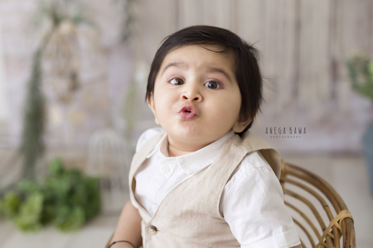 In this delightful baby pre-birthday photoshoot in Delhi, captured by Anega Bawa, a 11-month-old boy strikes a charming pout pose while seated amidst a bunch of leaves. His playful expression adds a touch of innocence and joy to the serene setting, creating beautiful memories to treasure for years to come.