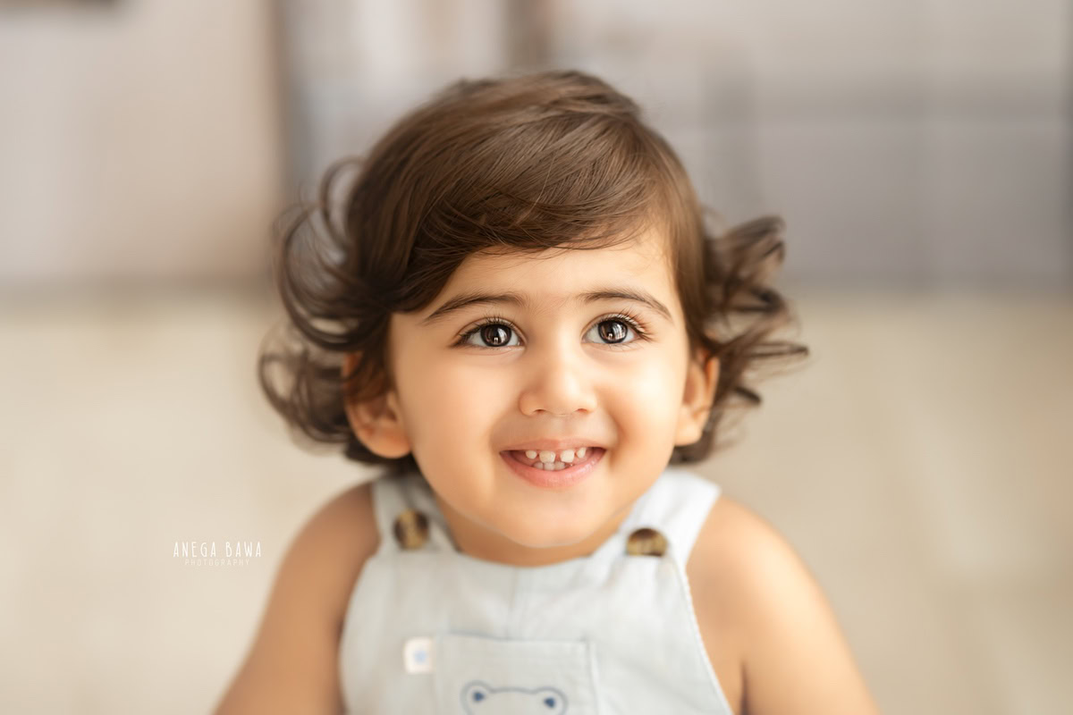 In this enchanting capture from a sitter photoshoot in Delhi, Gurgaon by Anega Bawa, a 14-month-old boy captivates with his enormous eyes. Against a sleek grey backdrop, his gaze is both curious and endearing, making for a timeless and captivating moment.