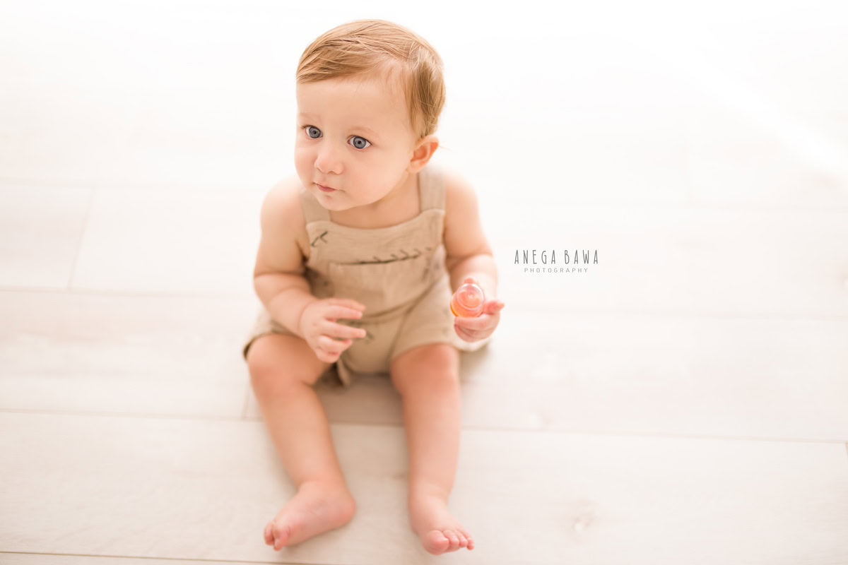 In Gurgaon, Anega Bawa, an accomplished sitter photographer, skillfully captures the charm of a 15-month-old boy seated on the floor against a pristine white backdrop. With expert lighting and composition, the photographer adeptly highlights the innocence and curiosity of the child in this captivating image.