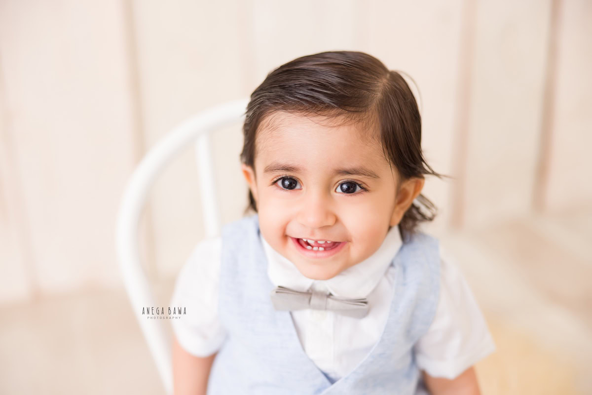 Captured by the lens of Gurgaon's accomplished sitter photographer, Anega Bawa, a 9-month to 1-year-old boy sits gracefully on a white chair. Set against a neutral beige backdrop, the scene exudes a sense of serenity and innocence, beautifully encapsulating this tender stage of childhood.