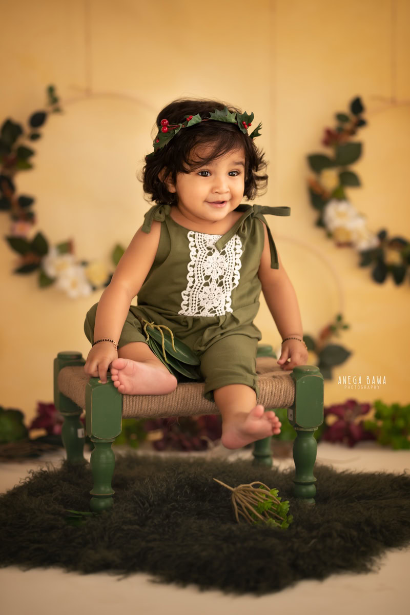Create beautiful memories of your 11-month to 1-year-old boy with a sitter photoshoot by Anega Bawa Photography in Delhi and Gurgaon. Against a vibrant yellow backdrop, let him sit on a cozy woven stool, adorned with a floral frame on the wall, capturing his innocence and charm in every frame.