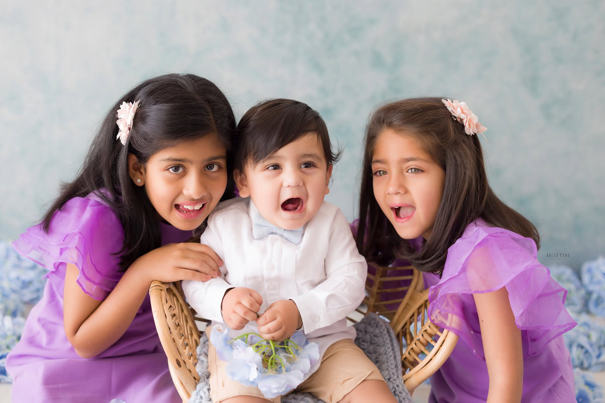 Delight in the charming sight of siblings seated on a blue rug against a serene blue backdrop, captured during a toddler photoshoot in Delhi, Gurgaon, and Noida by the talented photographer, Anega Bawa. These precious moments were immortalized when the children were 11 months to 1 year old.