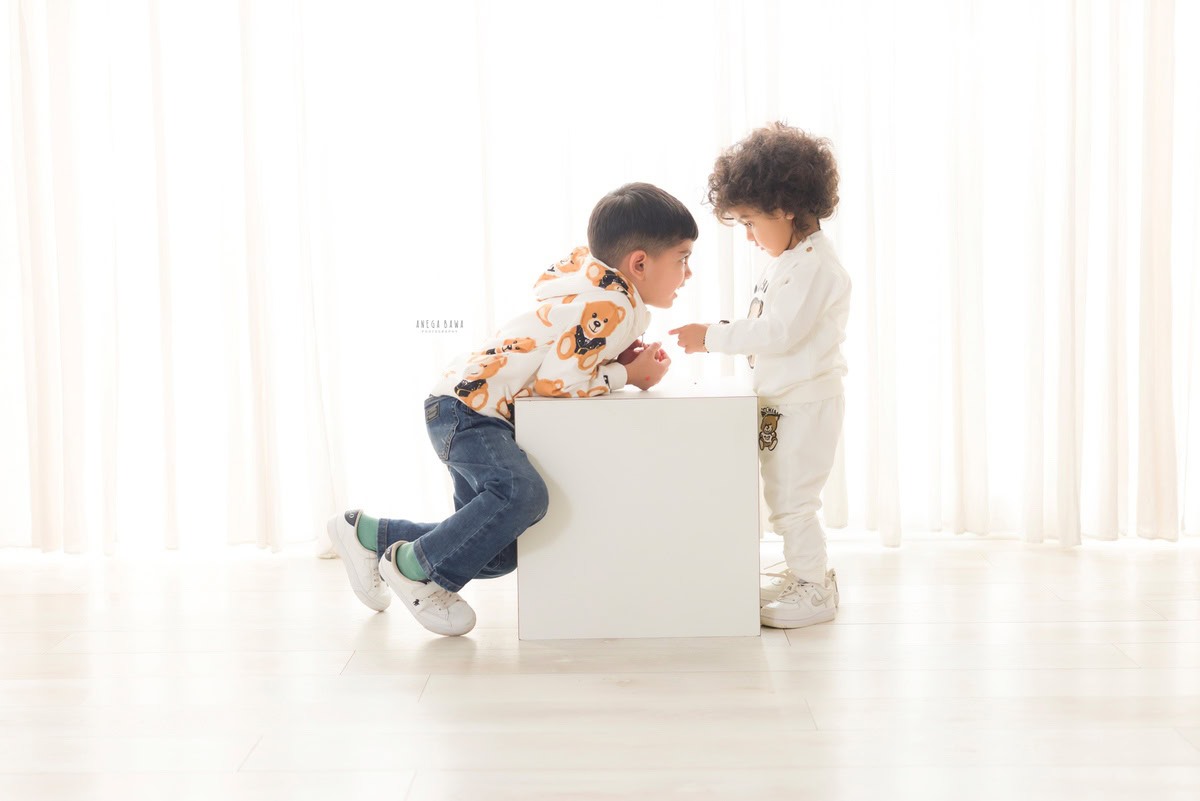 Capture the joyous bond of your little prince and his sibling with Anega Bawa Photography's sitter photography in Delhi and Gurgaon. Picture them seated together on a white stool, against a pristine white backdrop. Let their radiant smiles and playful camaraderie create timeless memories to cherish forever.