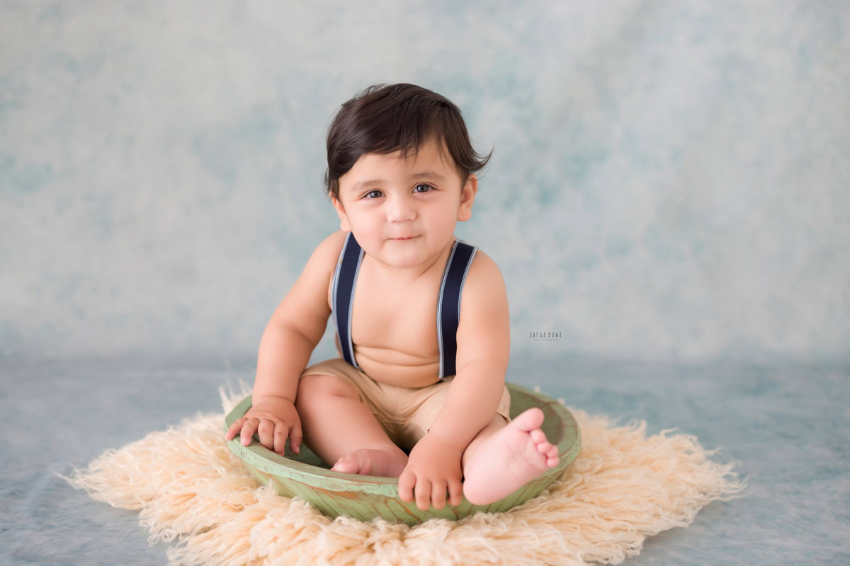 Immerse your little one in a world of enchantment with Anega Bawa Photography's sitter photography in Delhi and Gurgaon. Picture him sitting in a charming green tub, nestled on a beige rug, against a captivating blue backdrop. Let his innocence and curiosity shine through in every frame, creating magical memories to treasure for a lifetime.