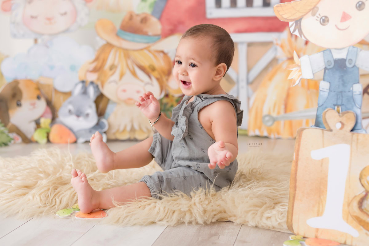 Immerse yourself in the magic of your little one's first steps into the world of photography with Anega Bawa Photography's sitter photoshoot in Delhi and Gurgaon. Delight in the sight of your 12-month-old boy sitting on a cozy beige rug against a whimsical cartoon backdrop. Each snapshot captures his innocence and wonder, creating timeless memories to cherish for years to come.