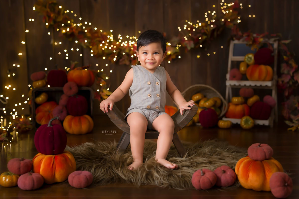 Capture the endearing essence of your little one with Anega Bawa Photography in Delhi and Gurgaon. In this delightful sitter photography session, your child, aged approximately 10 months to 1 year, is seated on a curvy chair. Bathed in the soft glow of golden lights, set against a cozy brown rug backdrop, each moment is a precious testament to your child's unique charm and personality. Let us freeze these cherished moments in time as your child explores the world with innocence and curiosity.