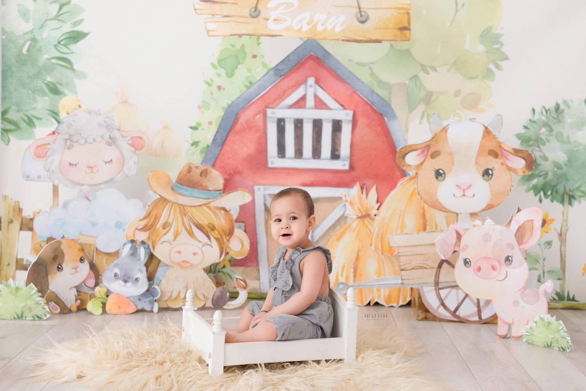 Boy seated on a pristine white cot against a whimsical cartoon backdrop, marking his journey from 9 months to 1 year old during his first birthday photoshoot in Delhi by Anega Bawa, Gurgaon, Noida.