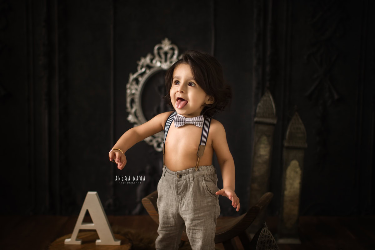 Delight in the innocence of your little one during a sitter photoshoot by Anega Bawa Photography in Delhi and Gurgaon. With a charming brown backdrop adorned with a bow and an alphabet frame, your 8-month to 1-year-old boy stands in sweet splendor, capturing precious memories to last a lifetime.