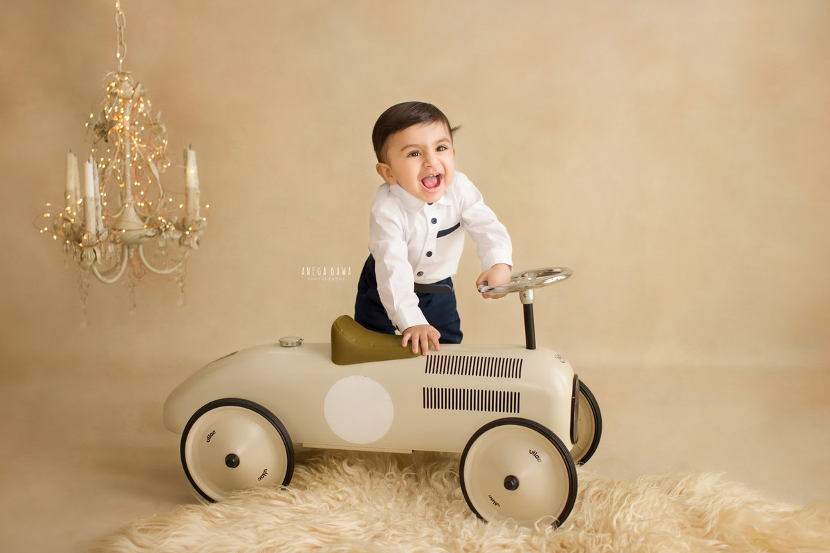 Let Anega Bawa Photography in Delhi and Gurgaon capture the joy of your little boy's milestones. Standing proudly with his toy scooter on a cozy beige rug against a matching backdrop adorned with candles and golden lights, your 8-month to 1-year-old shines in every frame, creating treasured memories to last a lifetime.