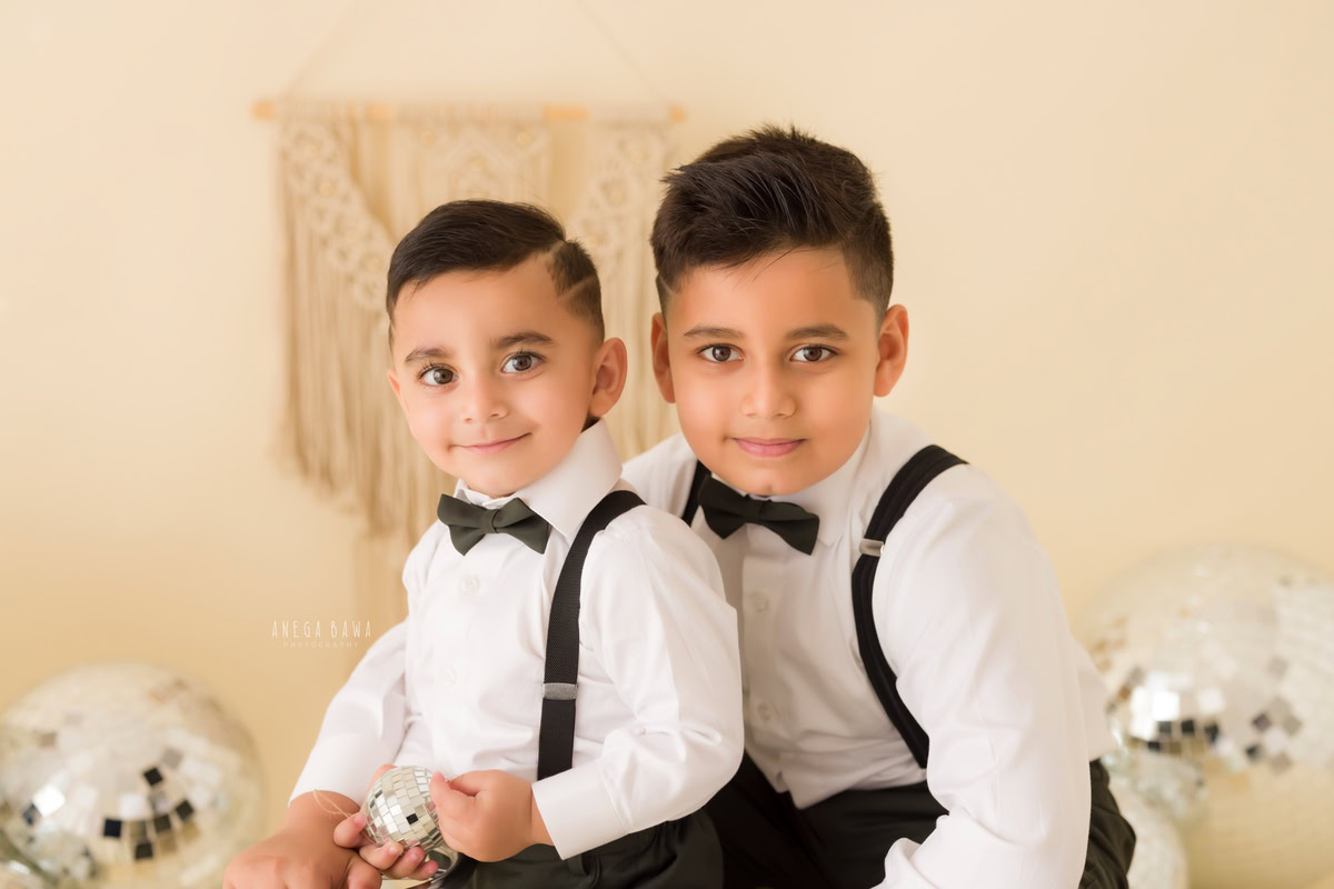 For this captivating shot, twin boys, aged between 8 months and 1 year, don stylish bow ties and white shirts against a beige backdrop adorned with disco balls. The photo was taken during a baby pre-birthday photoshoot in Delhi, Anega Bawa, Gurgaon, and Noida.