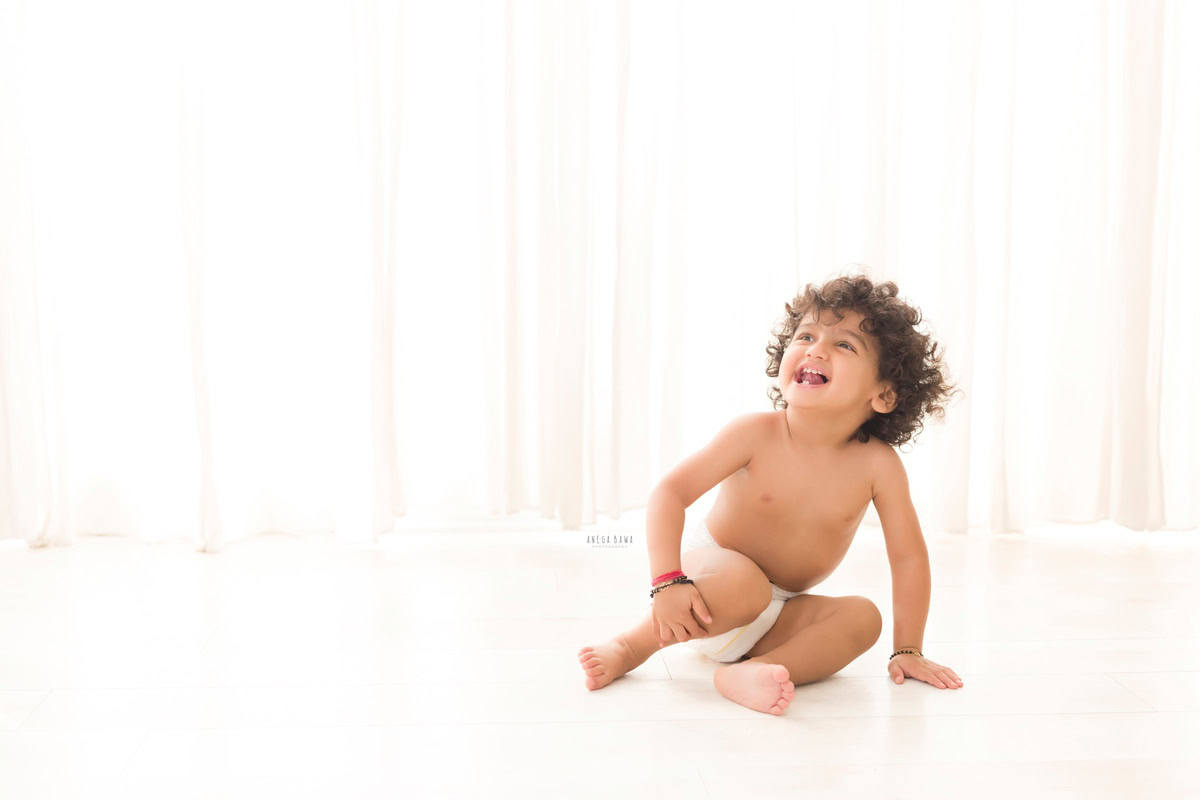 During a baby pre-birthday photoshoot in Delhi, Anega Bawa, Gurgaon, and Noida, a 12-month-old boy poses against a crisp white backdrop, showcasing his adorable charm in Pampers attire.