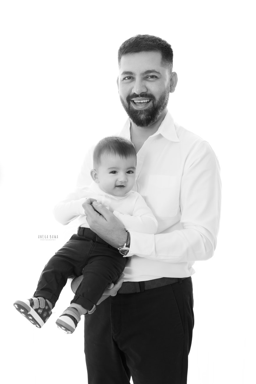 In Delhi and Gurgaon, Anega Bawa Photography captures the essence of familial love as a father and son strike a pose clad in white shirts and black denims against a pristine white backdrop, creating timeless memories to cherish for years to come.