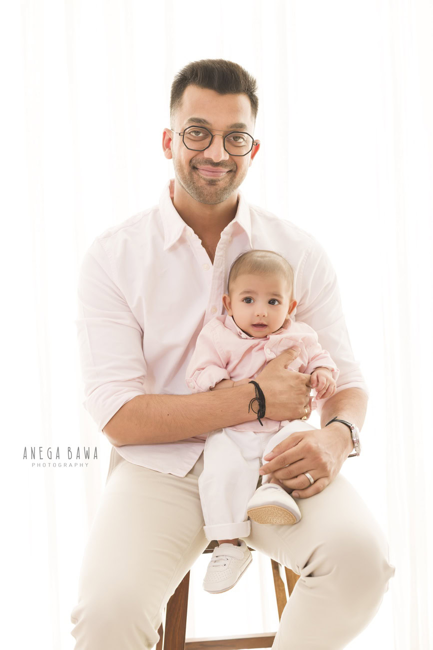 Delhi and Gurgaon offer the perfect backdrop for Anega Bawa Photography's family photoshoots. In this session, a father and son sit together on a wooden stool, framed against a clean white backdrop, capturing their bond in timeless elegance.