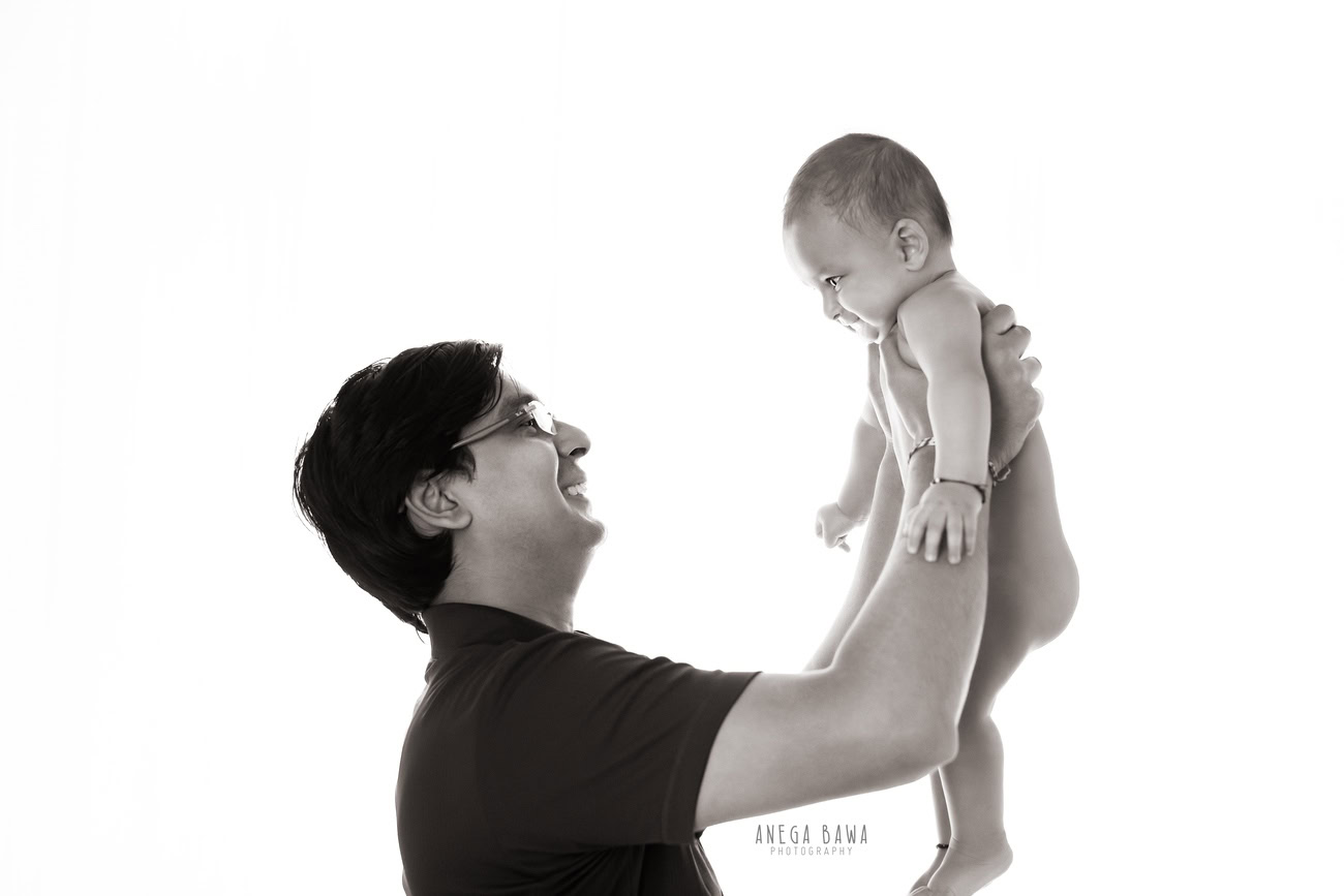 Create lasting memories with Anega Bawa Photography in Delhi and Gurgaon as a father shares precious moments with his son against a timeless white backdrop. Let the bond between them shine through in every frame, capturing the essence of their love and connection.