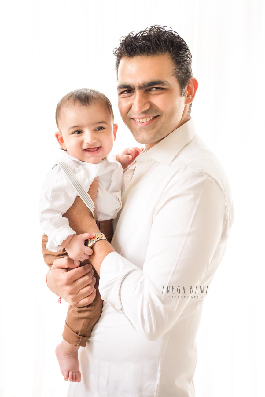Capture the joy of fatherhood with Anega Bawa Photography in Delhi and Gurgaon as a dad and his son don matching white shirts against a pristine white backdrop. Let the purity of their bond shine through in each frame, preserving these precious moments for a lifetime.