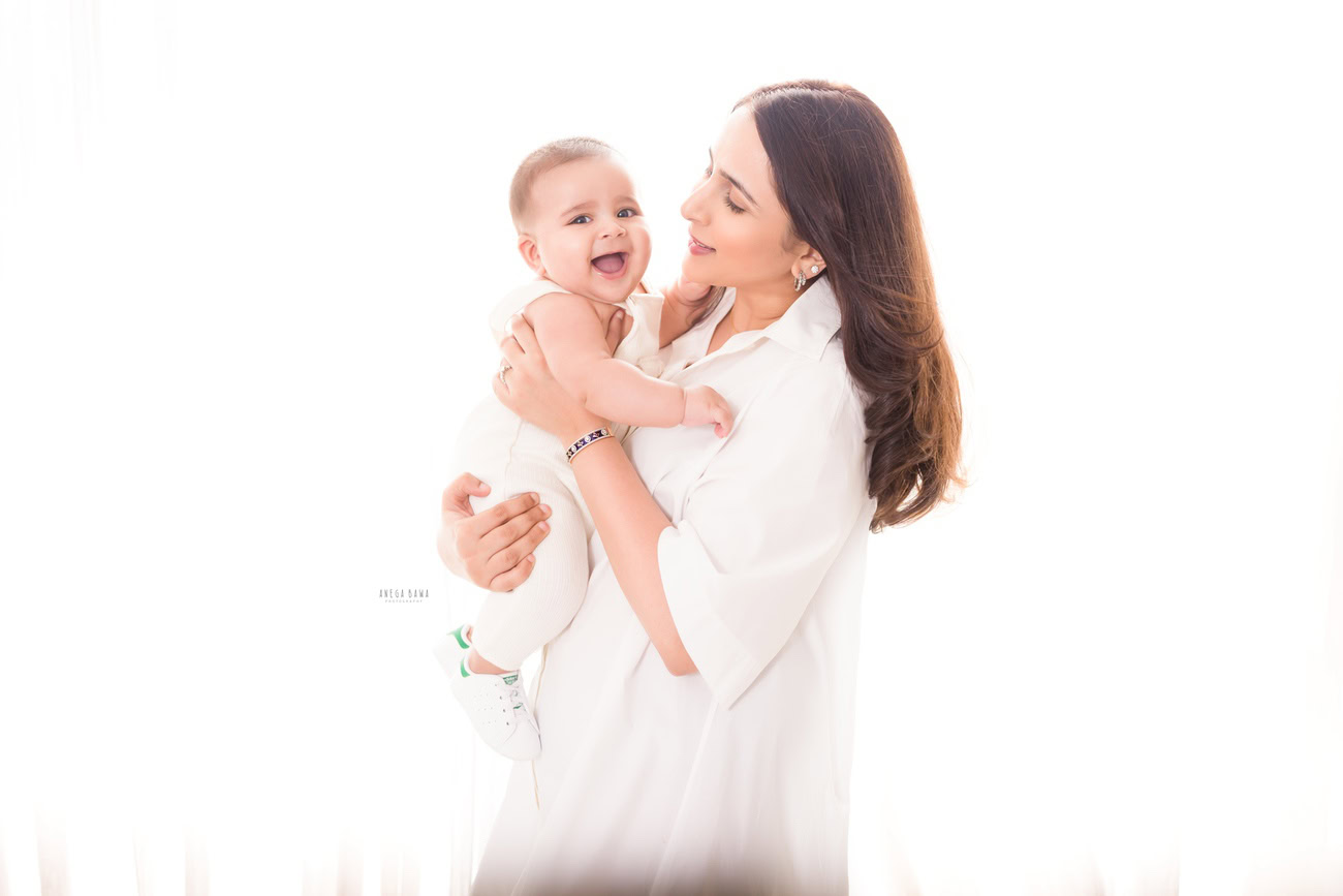Captivating family photoshoot by Anega Bawa Photography, renowned in Delhi and Gurgaon, showcasing the joyous smiling pose of Mom and girl against a pristine white backdrop.