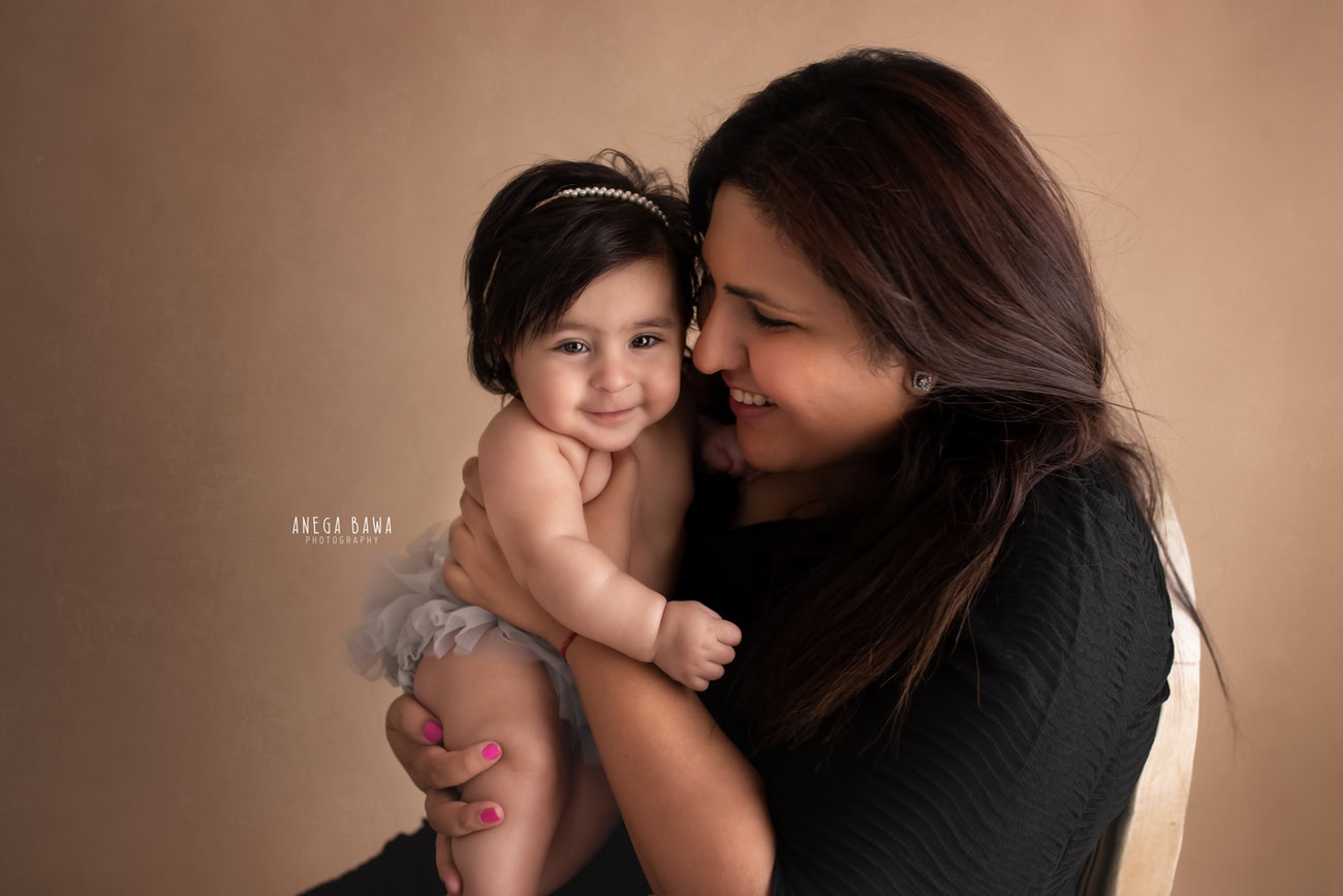 Captivating family photoshoot by Anega Bawa Photography, cherished in Delhi and Gurgaon, capturing the tender moment of Mom holding her daughter against a dusky brown backdrop.