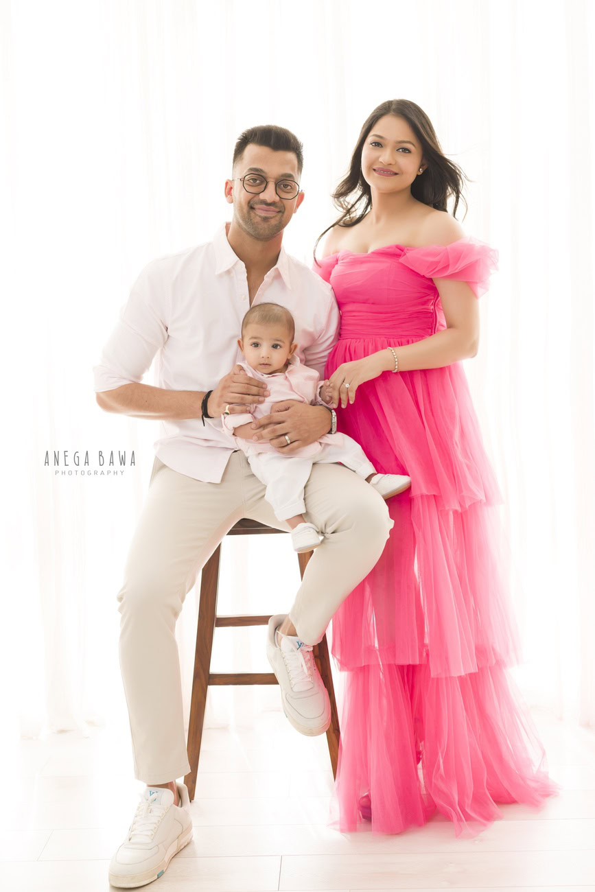 Captivating family photoshoot by Anega Bawa Photography, celebrated in Delhi and Gurgaon, featuring Mom in a pink dress, Dad, and son posing adorably against a pristine white backdrop.