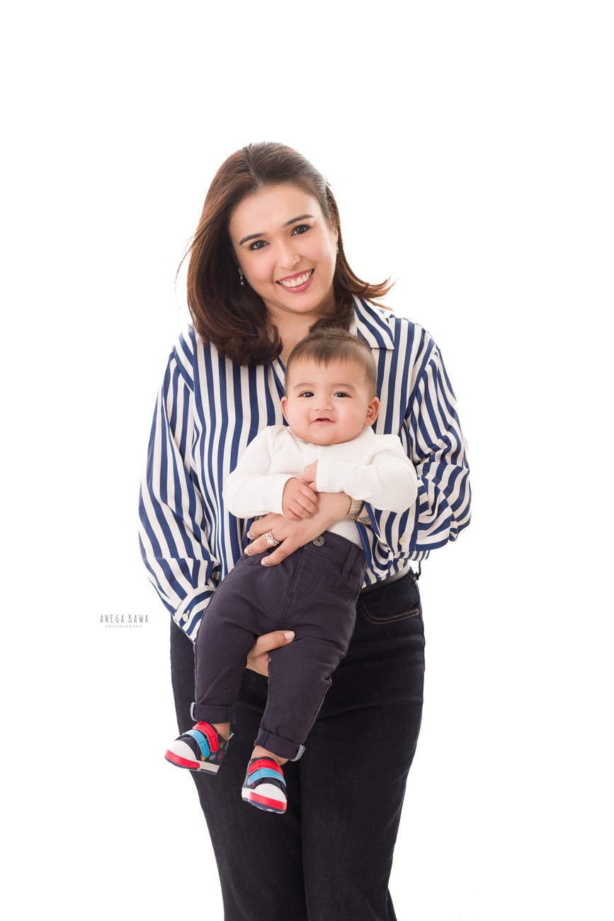 Captivating family photoshoot by Anega Bawa Photography, esteemed in Delhi and Gurgaon, showcasing a heartwarming moment of Mom posing cutely with her son against a pristine white backdrop.