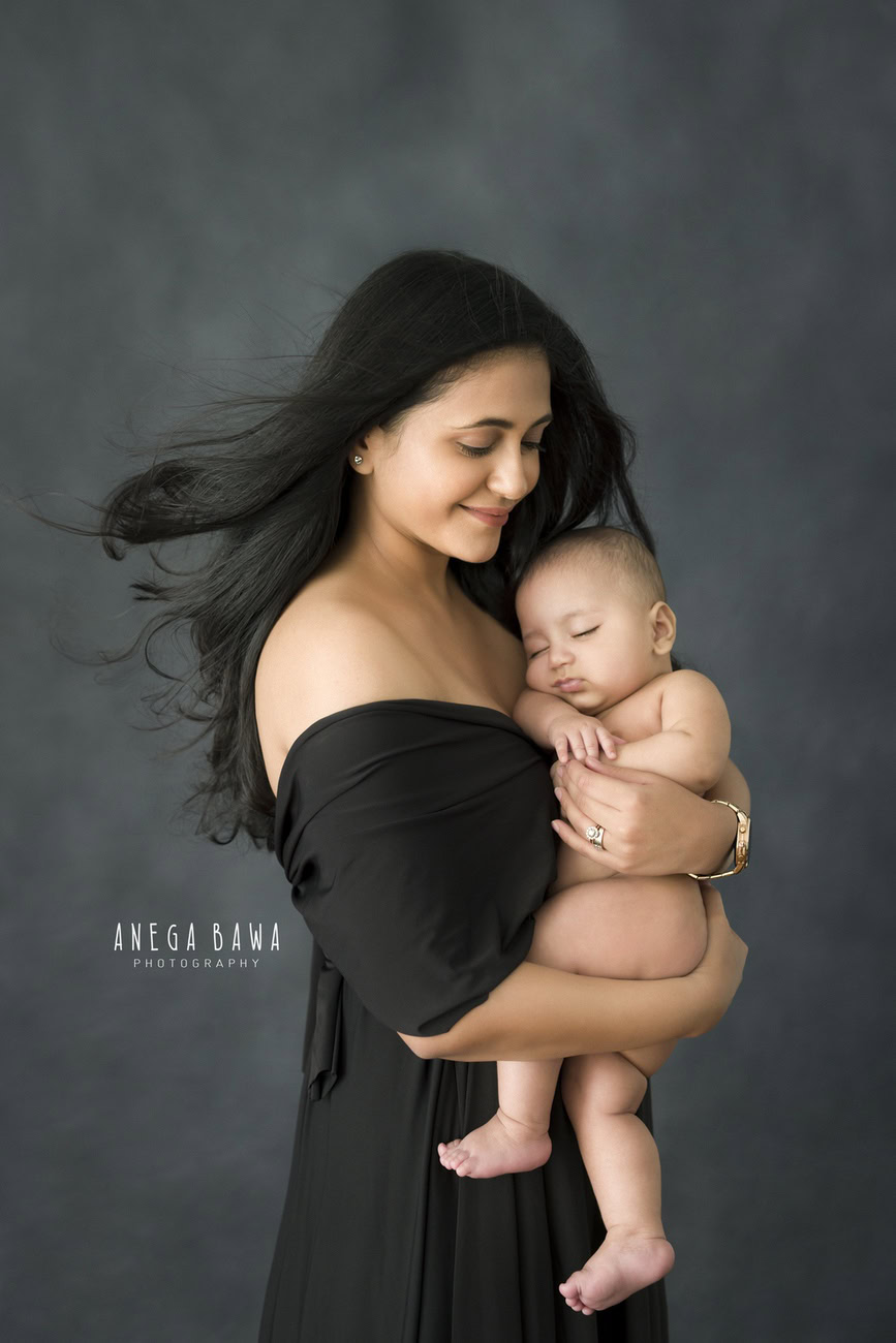 Delhi and Gurgaon's beloved Anega Bawa Photography presents a heartwarming family photoshoot featuring Mom and son in a tender hugging pose against a soothing grey backdrop.