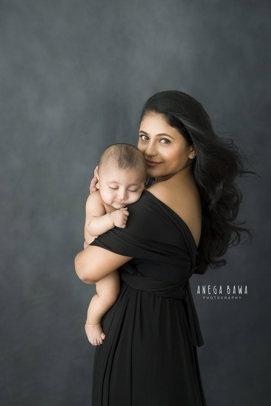 Delhi and Gurgaon's prestigious Anega Bawa Photography presents an endearing family photoshoot capturing precious moments between Mom and son in an adorable pose, set against a sophisticated grey backdrop.