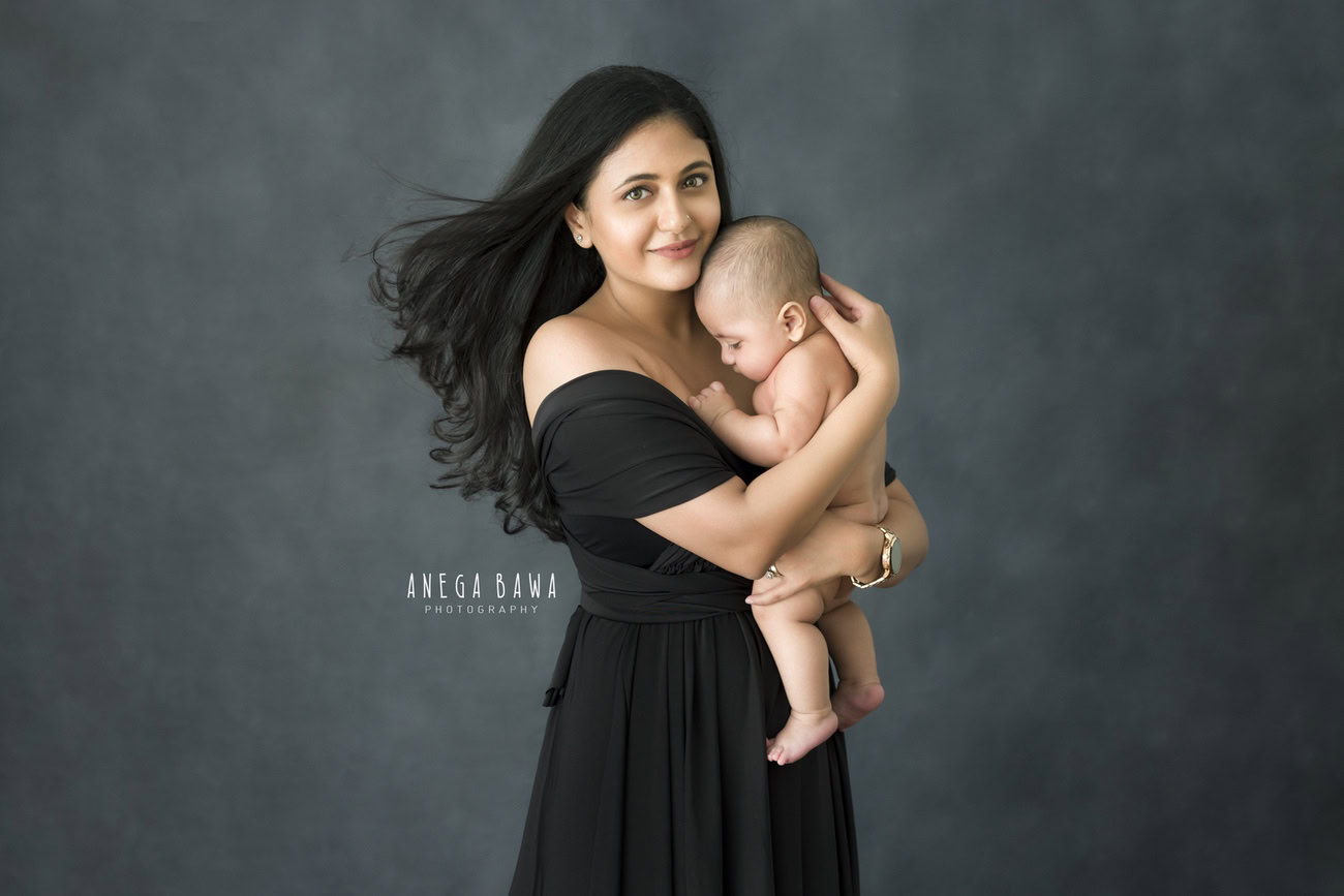 Experience the warmth of familial love with Anega Bawa Photography's exquisite family photoshoot. Witness the tender embrace between Mom and son, immortalized against a sleek grey backdrop. Located in Delhi and Gurgaon, trust us to capture your cherished moments with finesse.