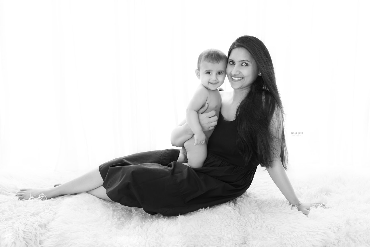 Embrace the bond of mother and son in a heartwarming family photoshoot by Anega Bawa Photography. Captured against a pristine white backdrop, experience the love and warmth shared as they sit together on a cozy beige rug. Located in Delhi and Gurgaon, our photography services ensure every moment is beautifully preserved.