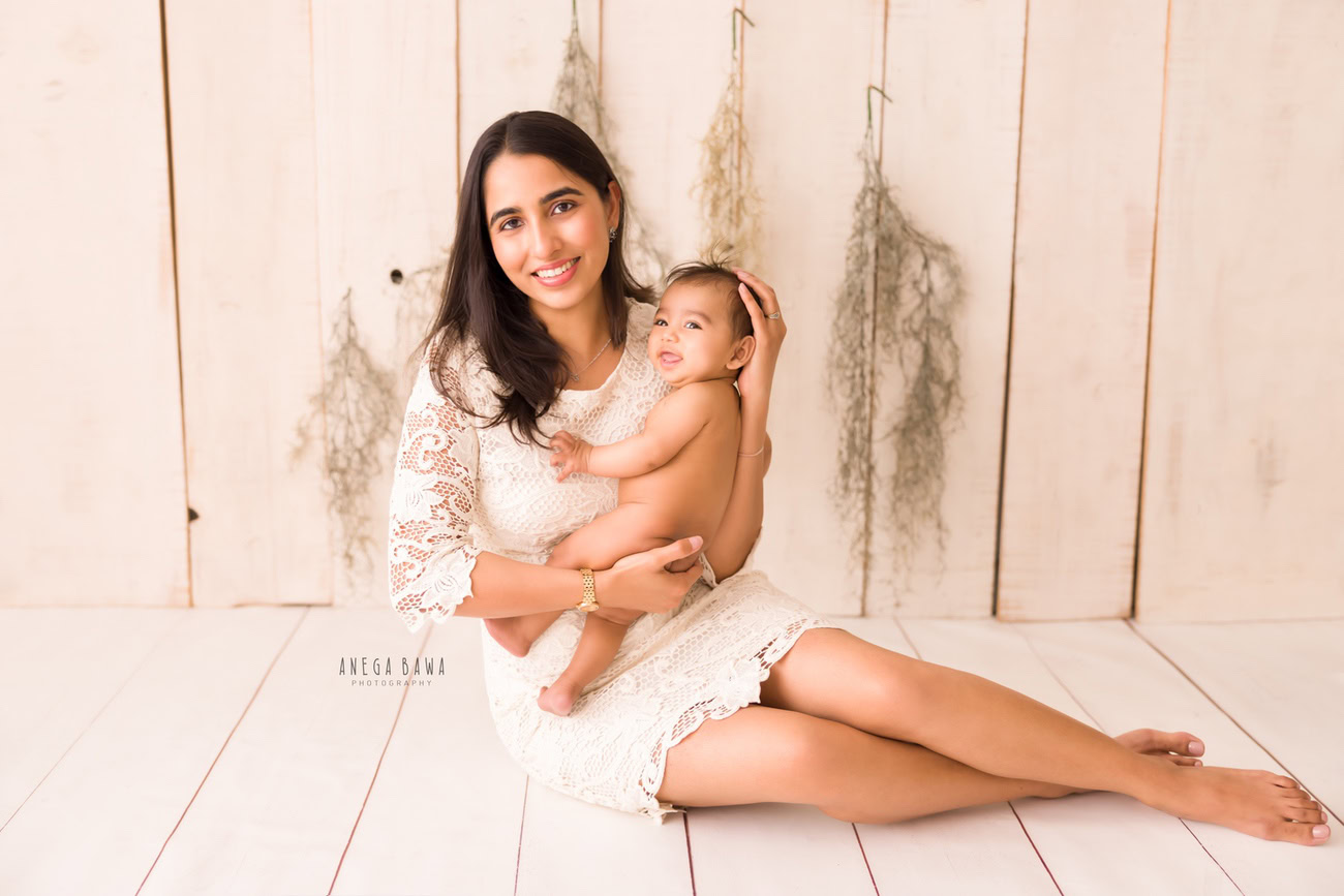 Celebrate the precious bond between a mother and her son with a heartwarming family photoshoot by Anega Bawa Photography. Set against a serene beige backdrop adorned with leafy fringes, capture the love and joy shared in every moment. Located in Delhi and Gurgaon, our photography services ensure memories that last a lifetime.