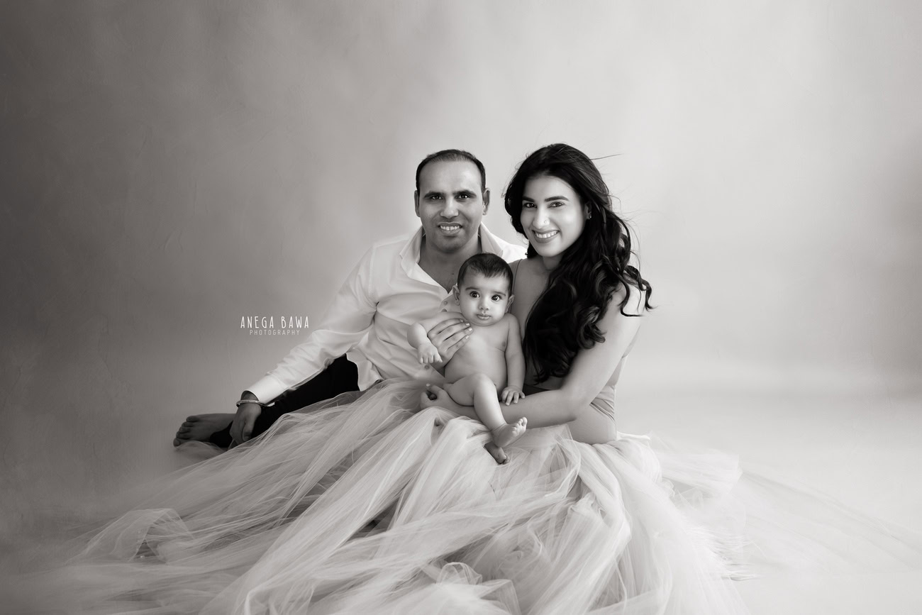 In the cozy warmth of a beige rug against a matching backdrop, Mumma, Papa, and their little boy create a timeless tableau in black-and-white, capturing the essence of familial love and unity. Let Anega Bawa Photography in Delhi and Gurgaon craft these enduring memories for your family to cherish for years to come.