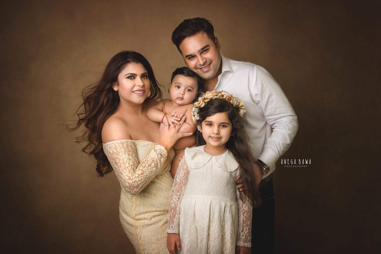 Celebrate your family's bond with a heartwarming photoshoot by Anega Bawa Photography in Delhi and Gurgaon. Let Mumma, Papa, Sister, and the little boy pose against a warm brown backdrop, capturing the essence of your family's love and togetherness.