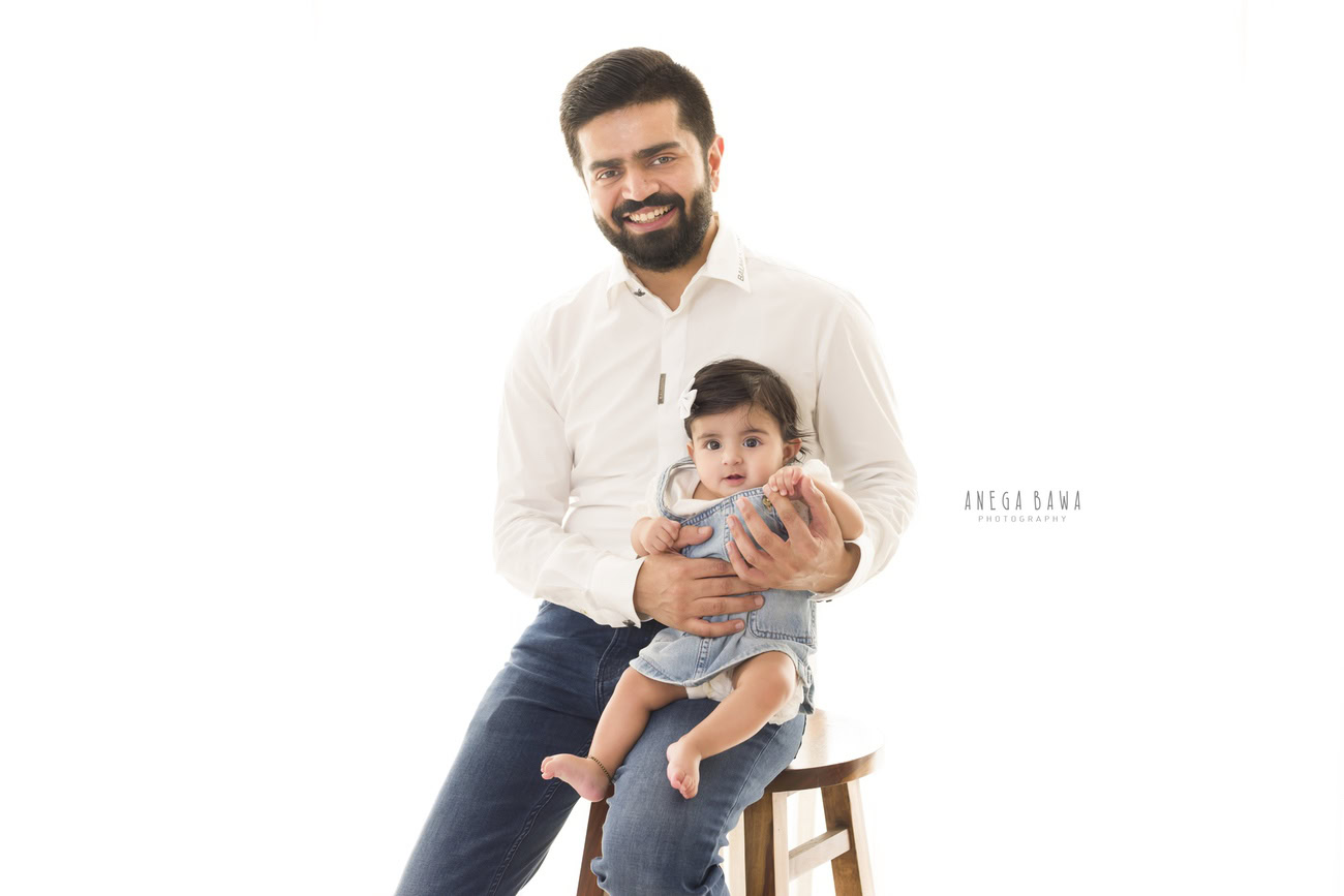 For a serene family moment, consider capturing Papa sitting on a stool, cradling his daughter on his lap, all set against a clean white backdrop. Anega Bawa Photography in Delhi and Gurgaon can beautifully encapsulate this tender moment, creating memories to treasure forever.